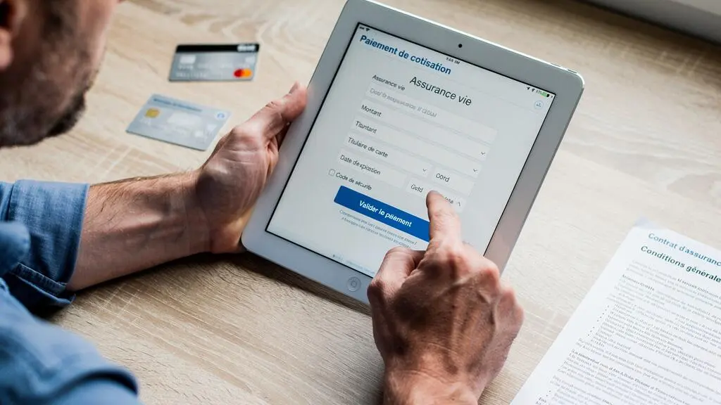 Mains d'une personne validant un versement sur une assurance vie via tablette numérique